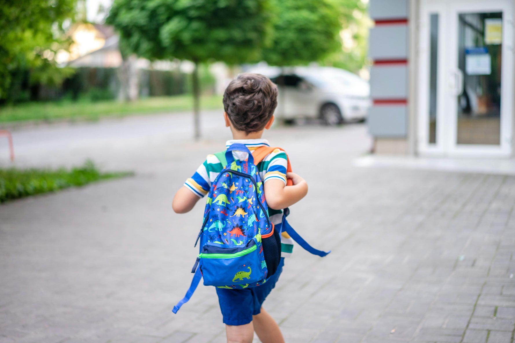 Child with a colorful backpack walking outside a building